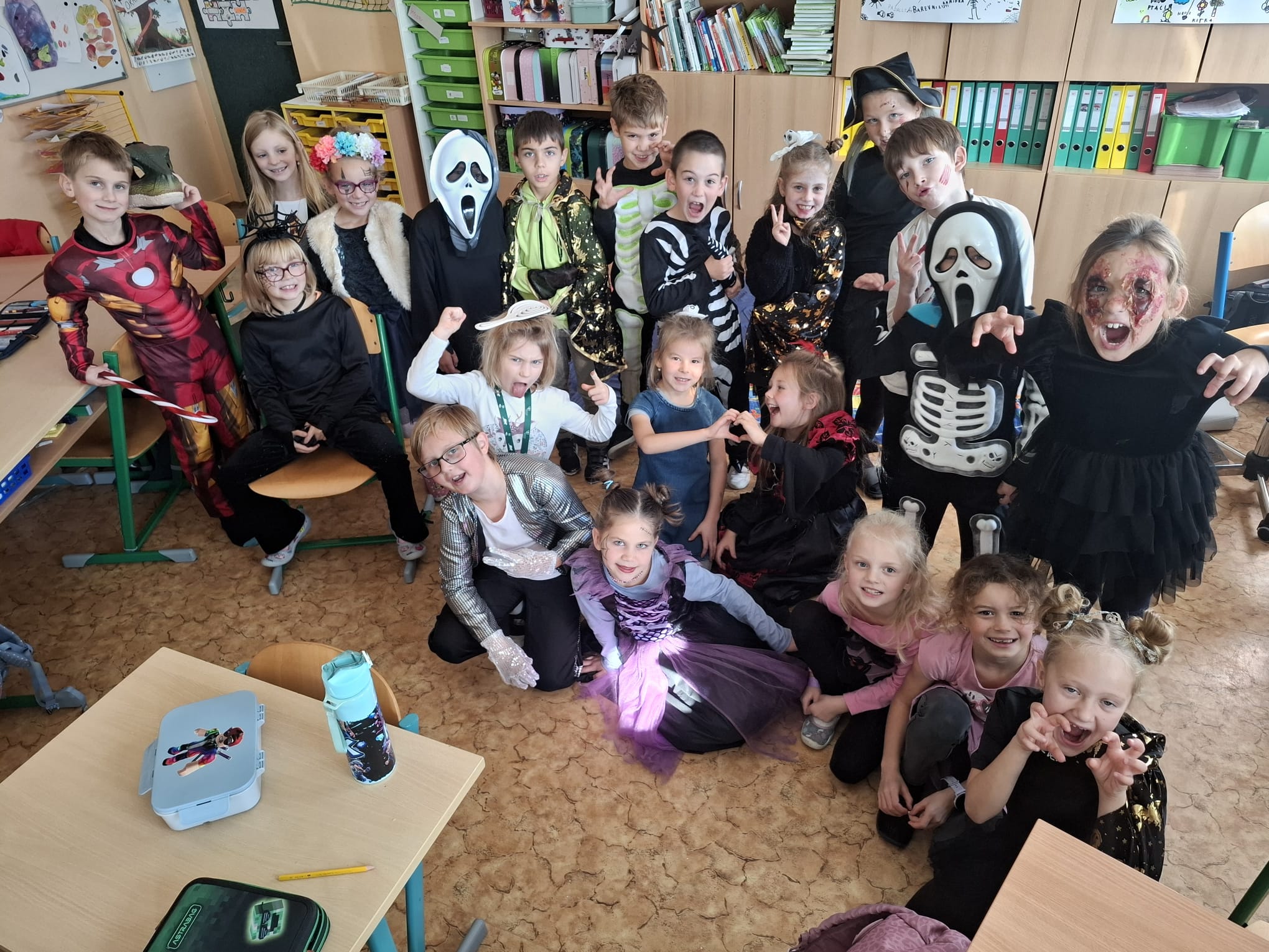 Velká skupina žáků v různých halloweenských kostýmech ve třídě