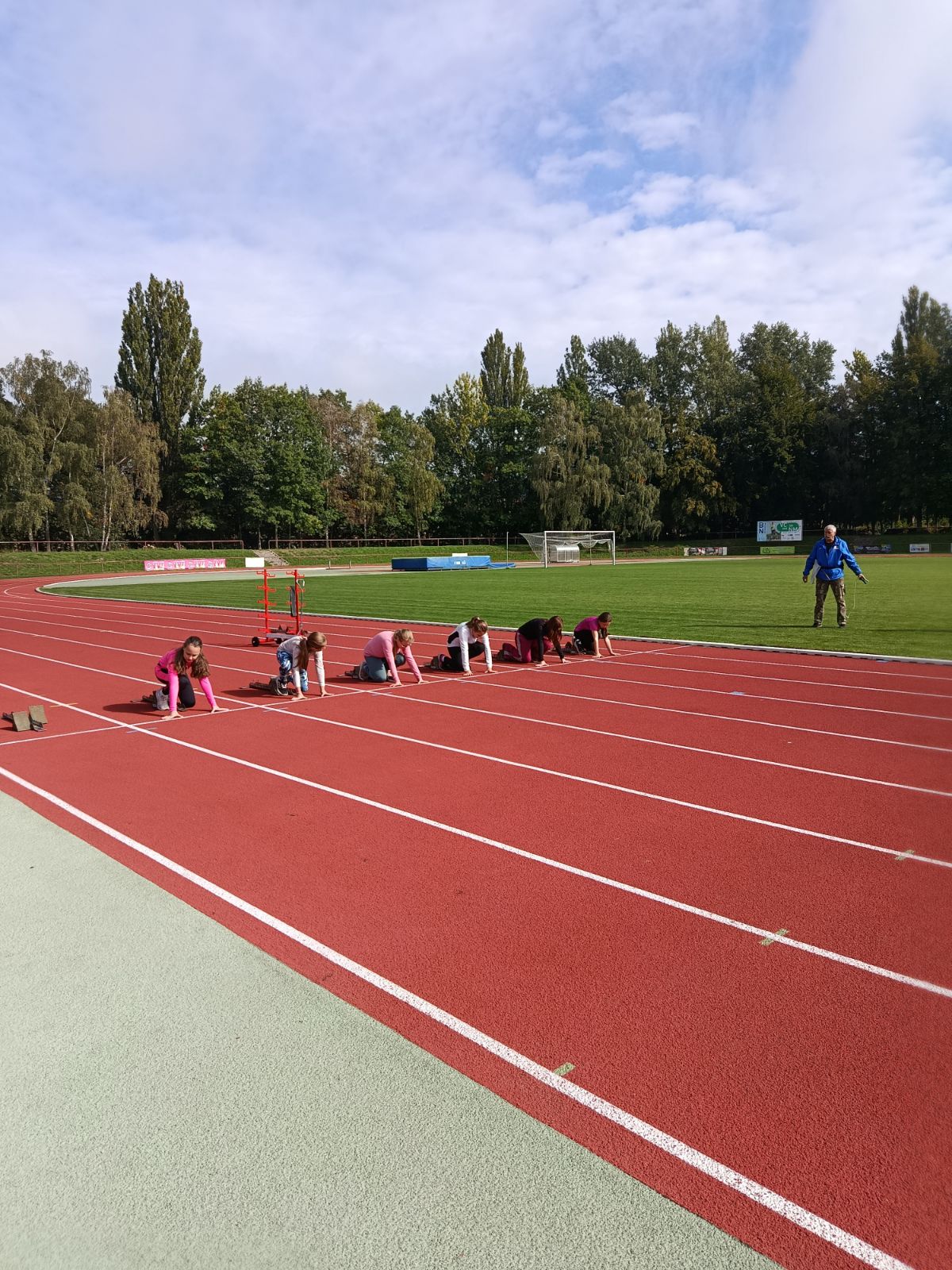 Žáci na atletickém stadionu čekají na start běžeckého závodu.